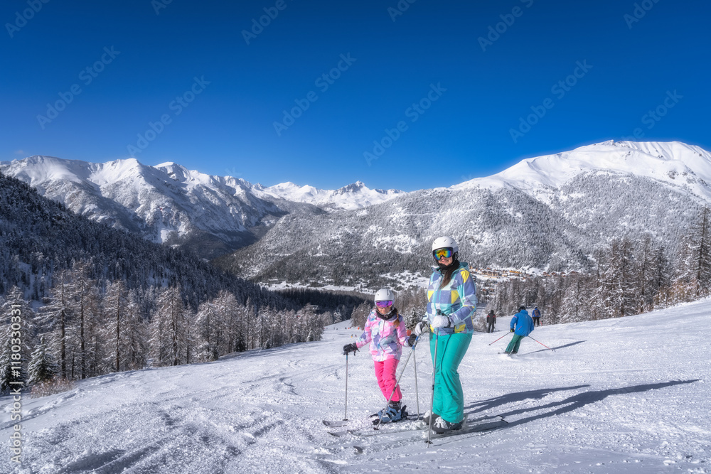 A joyful family is skiing together in a beautiful and scenic snowy landscape, surrounded by majestic mountains that rise high, all beneath a clear and bright blue sky, Montgenevre, Alps, France A joyful family is skiing together in a beautiful and scenic snowy landscape, surrounded by majestic mountains that rise high, all beneath a clear and bright blue sky, Montgenevre, Alps, France