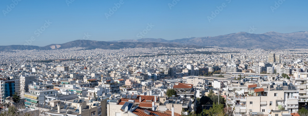 Panoramic photo shows the west north suburbs of Athens city on a sunny day. Blue sky and mountains at the background. Panoramic photo shows the west north suburbs of Athens city on a sunny day. Blue sky and mountains at the background.