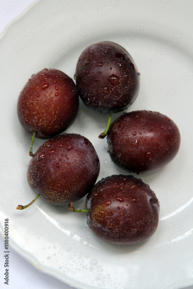 Fresh plums on the white plate
