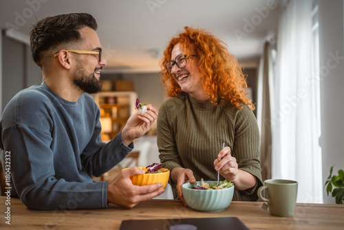 boyfriend and girlfriend eat salad and enjoy at breakfast at home
