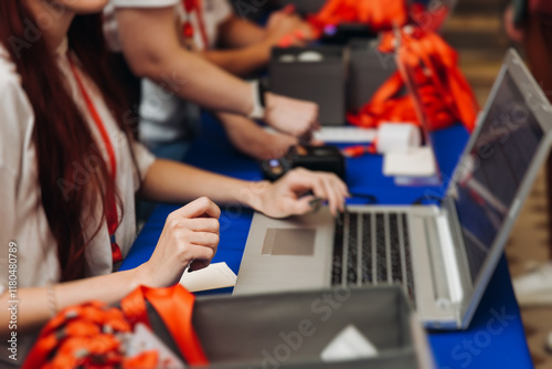 Process of checking in on conference congress forum event, registration desk table, visitors and attendees receiving lanyard with name badge and entry wristband bracelet and register electronic ticket
