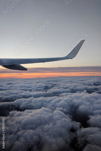 Airplane wing in the mid-air above fluffy clouds at sunset. Blue and pink evening cloudy sky, view from the airplane window. Boeing 737 on approach to land at Tenerife Airport, Canary Islands, Spain