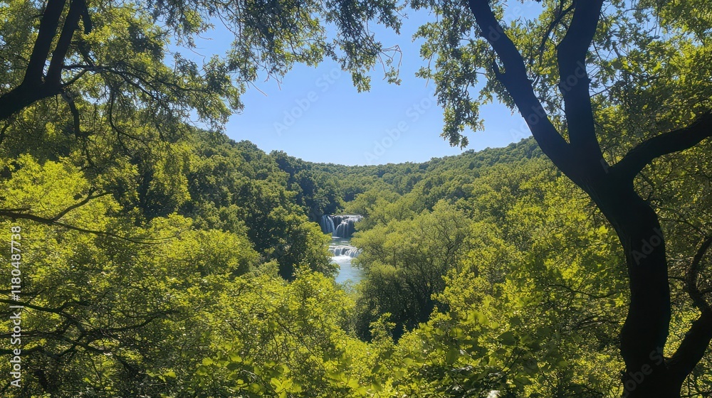 Fototapeta premium Waterfall in green forest viewed thru trees for background use