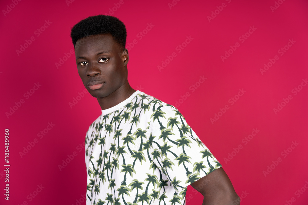 Obraz premium Young black man posing with tropical shirt on pink background