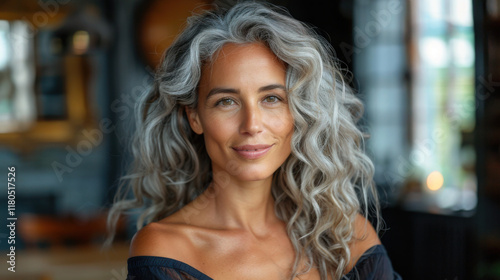 Wallpaper Mural A woman with voluminous, curly gray hair wearing an off-shoulder top, set against a blurred indoor background Torontodigital.ca