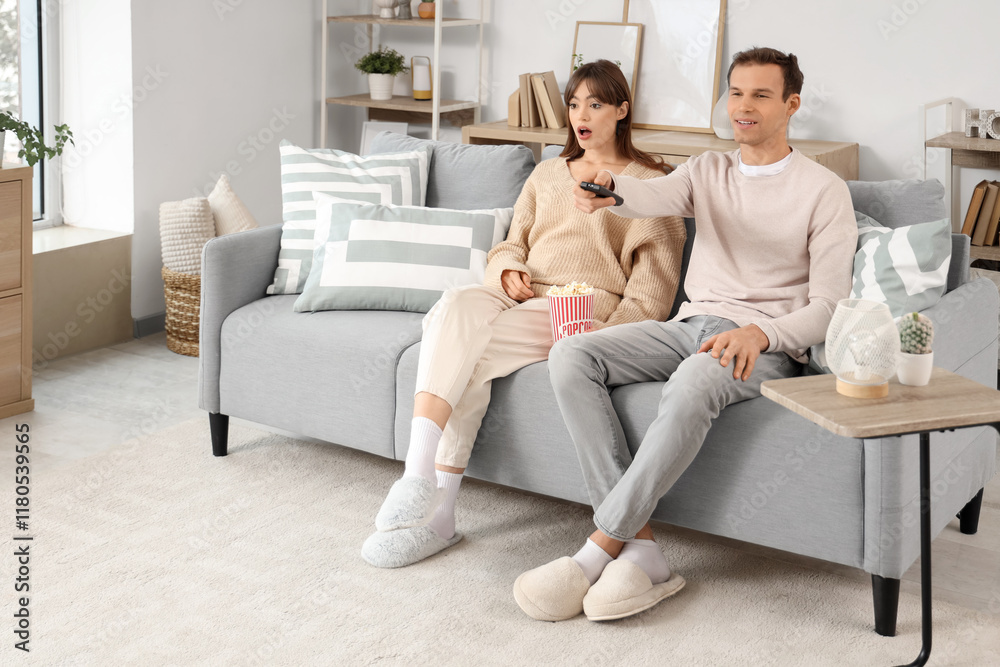 Young couple with popcorn watching TV on sofa at home Young couple with popcorn watching TV on sofa at home
