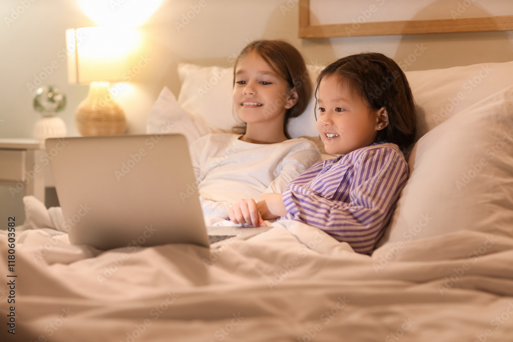 Cute girls watching cartoons on laptop in bedroom at night Cute girls watching cartoons on laptop in bedroom at night