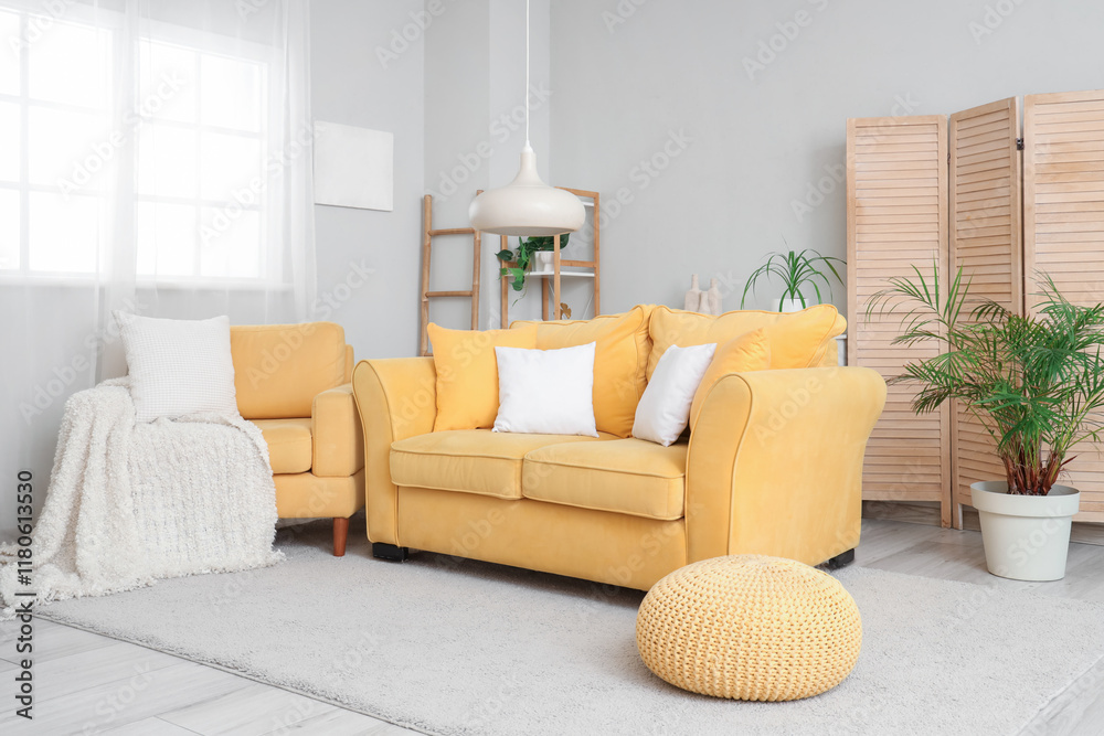 Obraz premium Interior of stylish living room with cozy yellow armchair, sofa and pouf