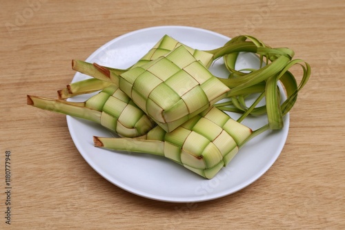 Ketupat or rice cake is served on a white plate on a wooden table. Traditional Indonesian food at Eid al-Fitr photo