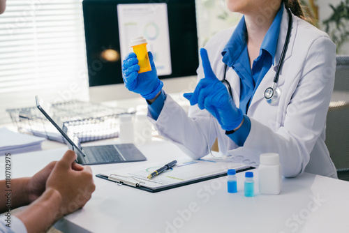 Fotografi Female doctor wearing blue gloves is holding a pill container and explaining med