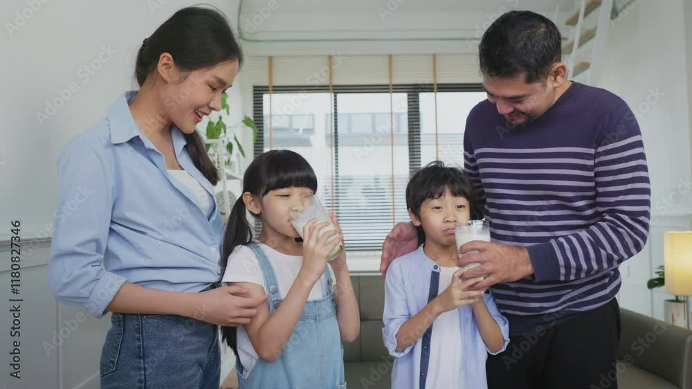 Asian family enjoying breakfast at cozy kitchen, little girl daughter sitting on table, drinking milk with smiling father and mother in morning. Happy family in kitchen. Asian family enjoying breakfast at cozy kitchen, little girl daughter sitting on table, drinking milk with smiling father and mother in morning. Happy family in kitchen.
