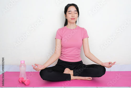 A woman wearing sportswear doing meditation above yoga mat photo