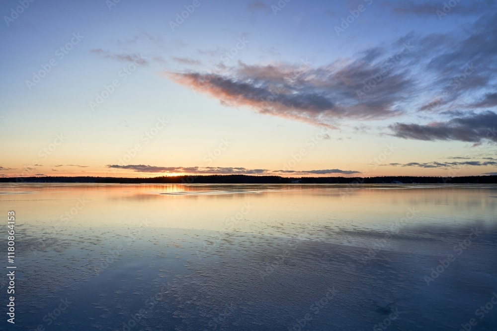 Fototapeta premium Serene sunset over a tranquil lake with a colorful sky reflecting on the water's surface.