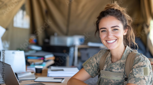 Australian woman in army uniform smiling, working with a laptop at tent