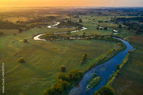 River flows in summer meadow, amazing landscape at sunrise