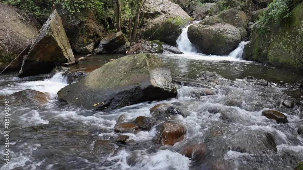 Small shallow forest river flows through large rock boulders, nature Small shallow forest river flows through large rock boulders, nature