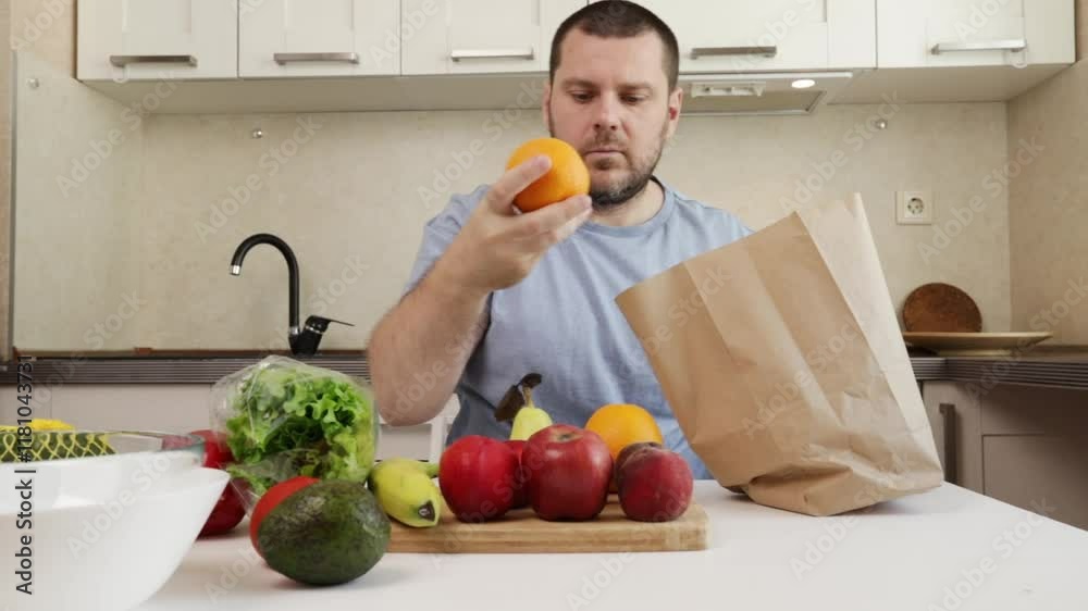 a man takes groceries out of a shopping bag, family meal preparation, indoor domestic kitchen with natural produce, healthy eating a man takes groceries out of a shopping bag, family meal preparation, indoor domestic kitchen with natural produce, healthy eating