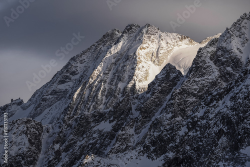 Panoramic view of mountains near Passo Tonale, Ponte di Legno, Italy. Large snowy mountain range under gray cloudy sky. Ski resort landscape on clear sunny day. Mountain ski resort. Snow slope photo