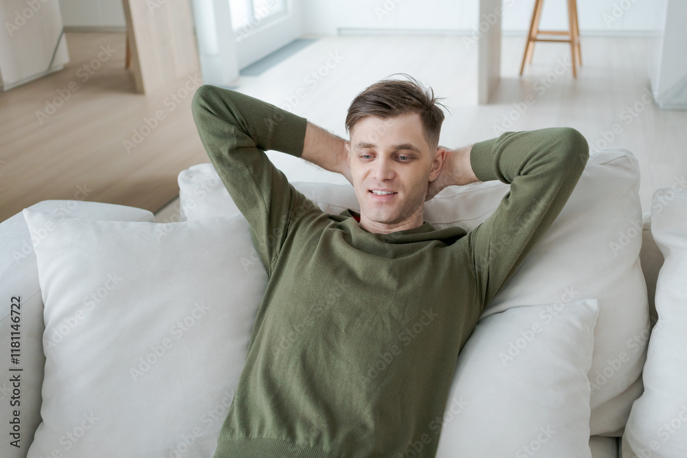 Man is laying on a couch with his arms crossed and a smile on his face Man is laying on a couch with his arms crossed and a smile on his face