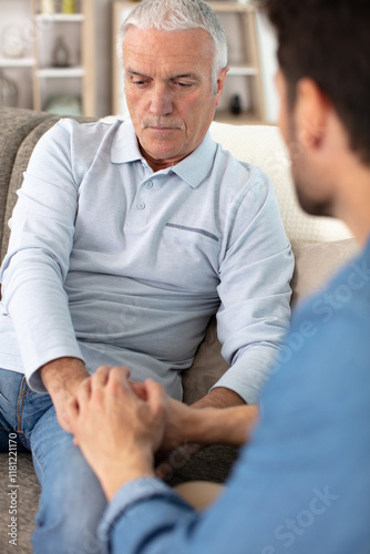 serious elderly father and grown-up adult son helping him