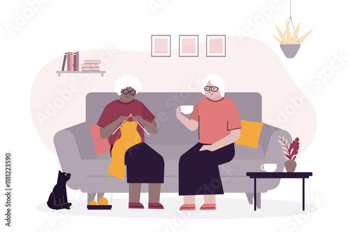 Elderly people spending relaxing day enjoying their hobbies sitting in living room at home knitting, talking and drinking tea. Aged women together,