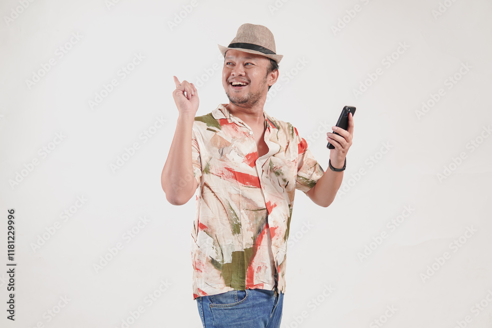Attractive Asian man holding smartphone while pointing to the copy space behind him. Attractive Asian man holding smartphone while pointing to the copy space behind him.