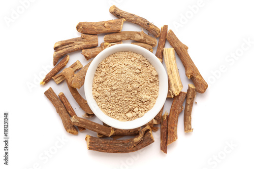 A bowl of Organic Liquorice or Mulethi (Glycyrrhiza glabra) powder, placed over a heap of liquorice roots. Isolated on a white background.