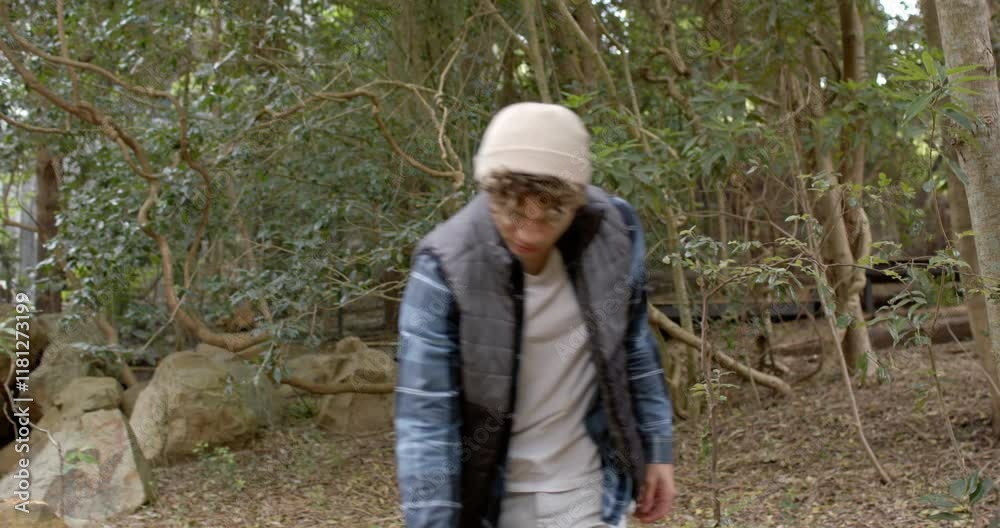 Young man exploring forest, wearing warm clothing, enjoying nature walk Young man exploring forest, wearing warm clothing, enjoying nature walk