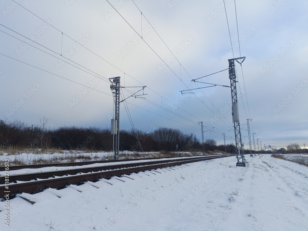 Two way railroad tracks in countryside. Two railway tracks. Sunny day. Countryside. Fields and trees. Snow is laying on ground. Two way railroad tracks in countryside. Two railway tracks. Sunny day. Countryside. Fields and trees. Snow is laying on ground.