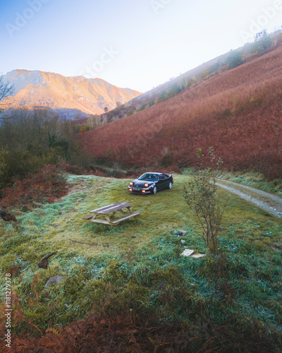 Accous, France - 15 November 2024: Aerial view of a serene and misty morning landscape with a road and car amidst the tranquil mountains and hillside, Accous, France. photo