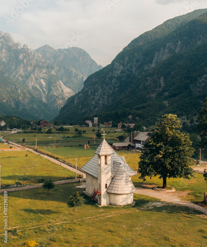 Aerial view of a picturesque village with a historical church nestled in a serene valley surrounded by majestic mountains and vibrant greenery, Shkoder, Albania. photo