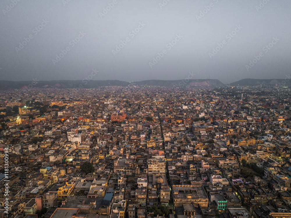 Aerial view of vibrant cityscape with sprawling buildings and hills at dusk, Jaipur, India.