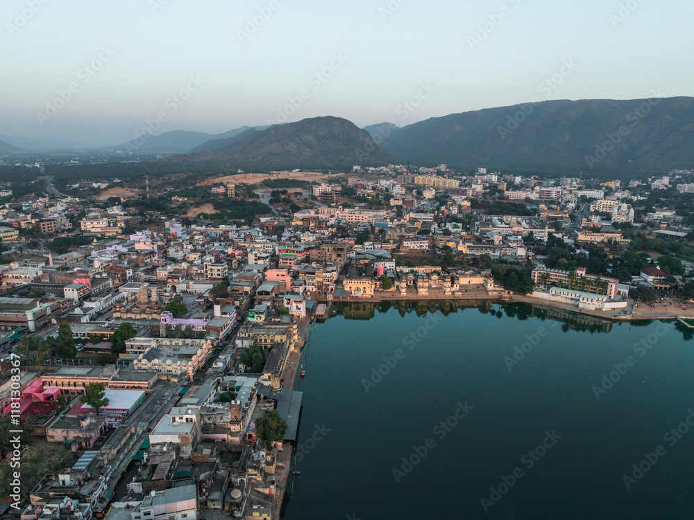 Aerial view of Pushkar Lake with ghats and picturesque buildings under a serene sunset, Pushkar, Rajasthan, India. Aerial view of Pushkar Lake with ghats and picturesque buildings under a serene sunset, Pushkar, Rajasthan, India.