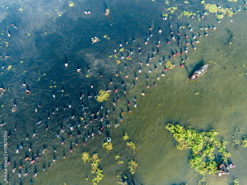 Aerial view of people engaged in traditional polo fishing on a river surrounded by lush greenery, Parbhanguria, Bangladesh.