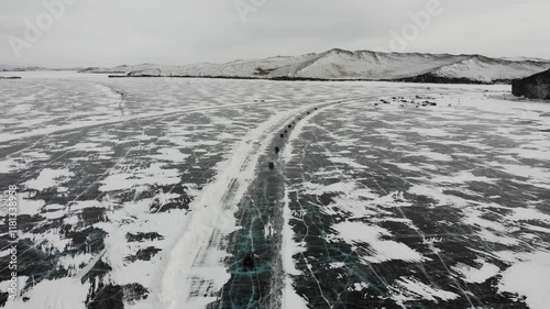 Ice road to Olkhon Island from the air.Cars drive along the ice road. Winter travel by car.