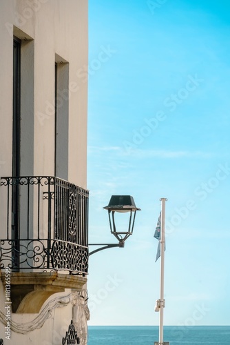 Obraz na płótnie A lamp post with a blue flag on top of it. The lamp post is on a balcony overlooking the ocean w salonie