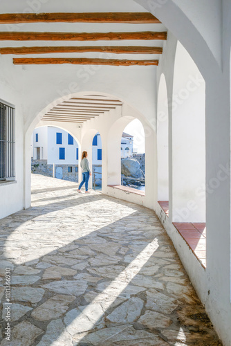 Obraz na płótnie A Tourist Girl Looking Through Of The Arches Of The Promenade Of The Tourist City Of Calella De Palafrugell, Costa Brava, Catalonia. Scenic fisherman village with nice sand beach and clear blue water w salonie