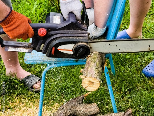 A man cuts down a tree with an electric saw. Sawdust flies in all directions from the chainsaw. Cutting wood with a chain saw