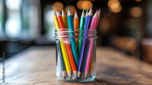 Colorful pencils arranged in a glass jar against a blue background