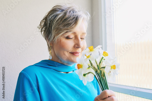 Spring portrait of beautiful 55 - 60 year old woman with daffodil flowers
