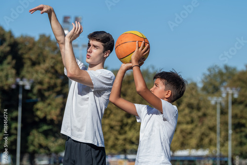 Carta da parati Outdoor basketball training for kids, featuring a coach teaching a young boy shooting technique
