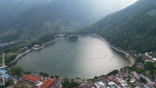 
The stunning Telaga Sarangan in Magetan glistens under the sky, surrounded by towering green mountains, offering a serene and breathtaking landscape. photo