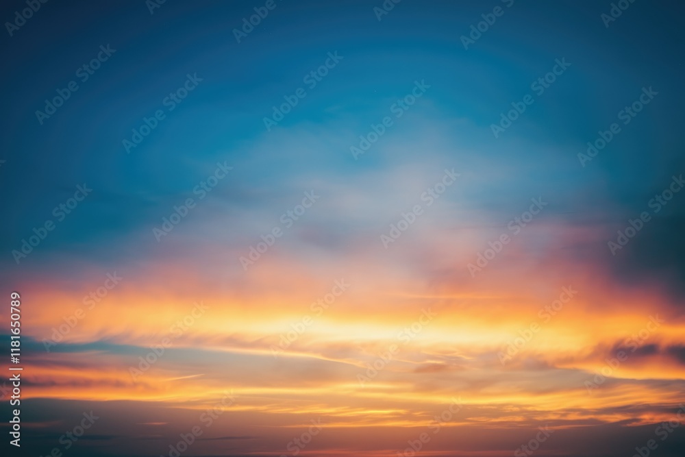 Fototapeta premium Vibrant sunset sky with orange, yellow, and blue hues, creating a breathtaking panorama.