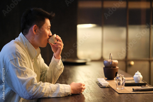 Canvas-taulu Chinese young man holding teacup drinking tea. Side view