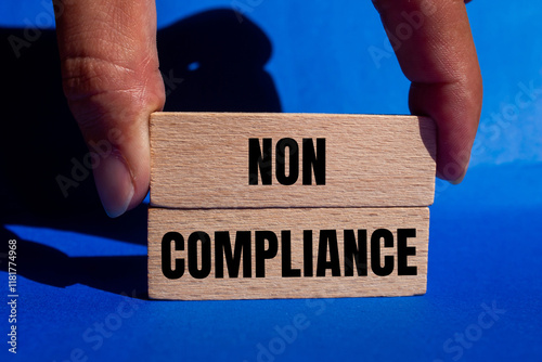 Non compliance message written on wooden blocks with blue background. Conceptual non compliance symbol. Copy space.