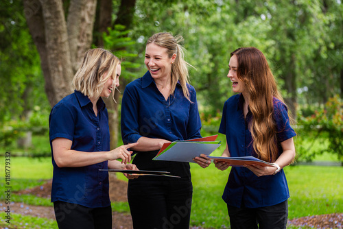 Three female speech pathologists holding phonics resources chatting together  photo