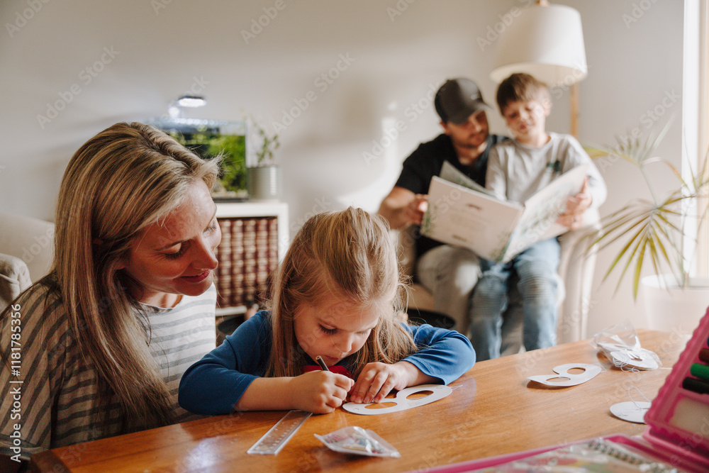 Mum helping daughter with her artwork on the table. Mum helping daughter with her artwork on the table.