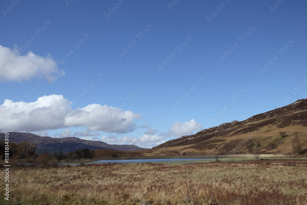 Scenic view of Scottish landscape featuring a tranquil lake and rolling hills under a clear blue sky Scenic view of Scottish landscape featuring a tranquil lake and rolling hills under a clear blue sky