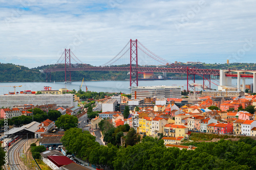 Generated imageSuspension bridge Ponte 25 de Abril in Lisbon, Portugal. View of colourful facades and The 25th April Bridge over river Tajo. Travel summer photography. photo