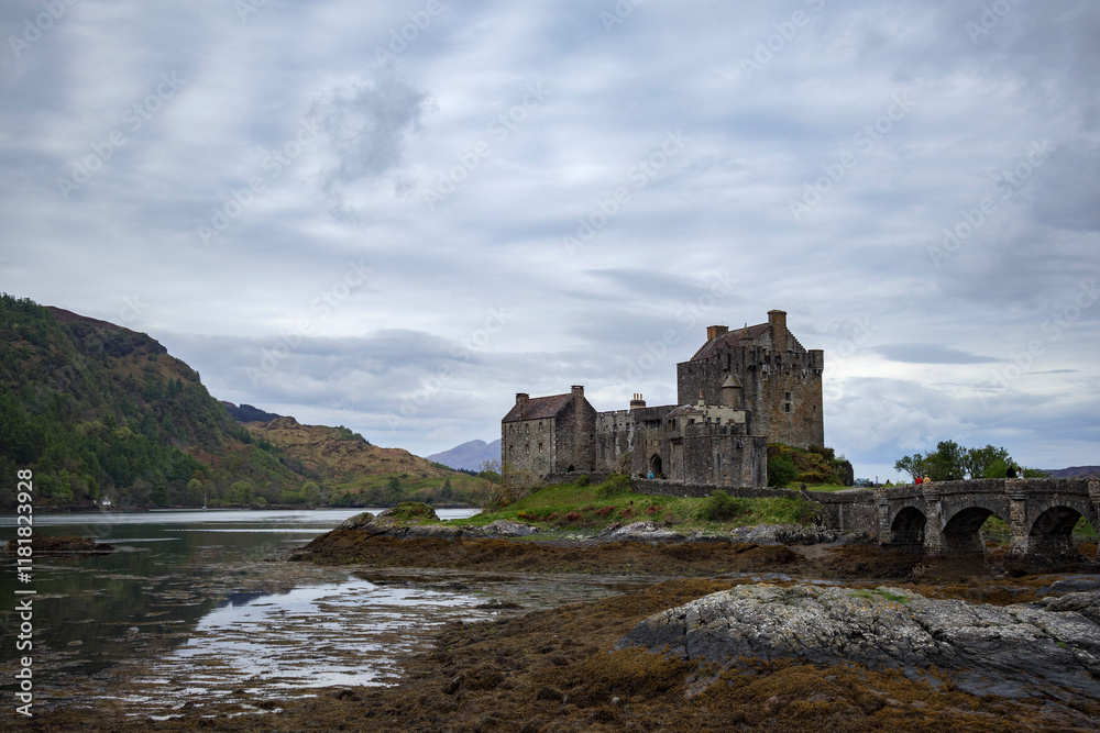 Historic castle on the shores of a loch in Scotland surrounded by dramatic landscapes and cloudy skies Historic castle on the shores of a loch in Scotland surrounded by dramatic landscapes and cloudy skies